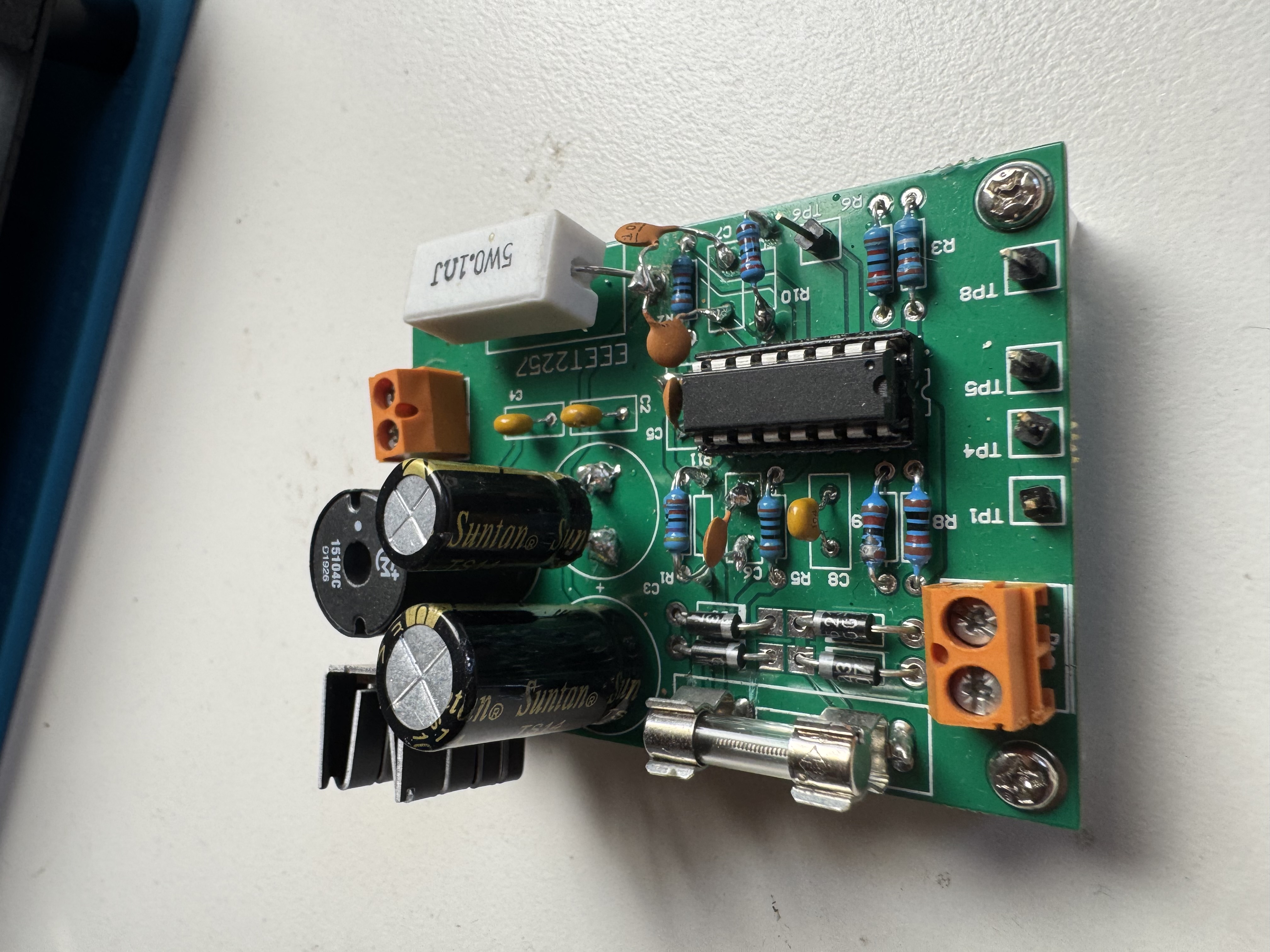 RMIT EEET2257 pre-fabricated PCB used for Engineering Design 2 testing — green PCB with electrolytic capacitors, DIP IC, resistors, diodes, and orange terminal blocks
